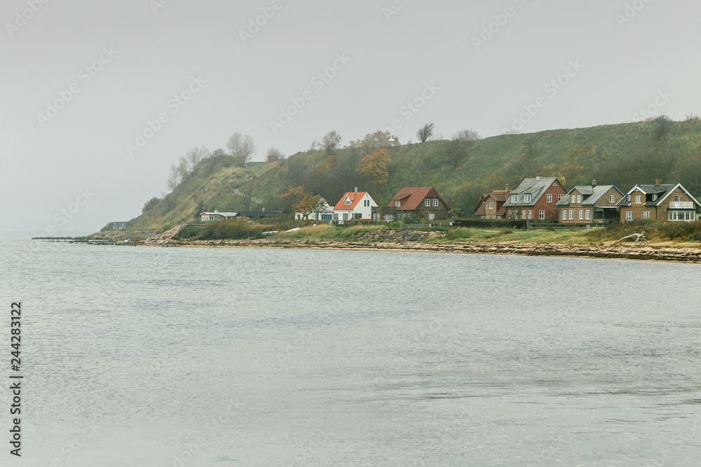 Island Ven in Oresund between Denmark and Sweden with houses close to the beach down the hills in cloudy day