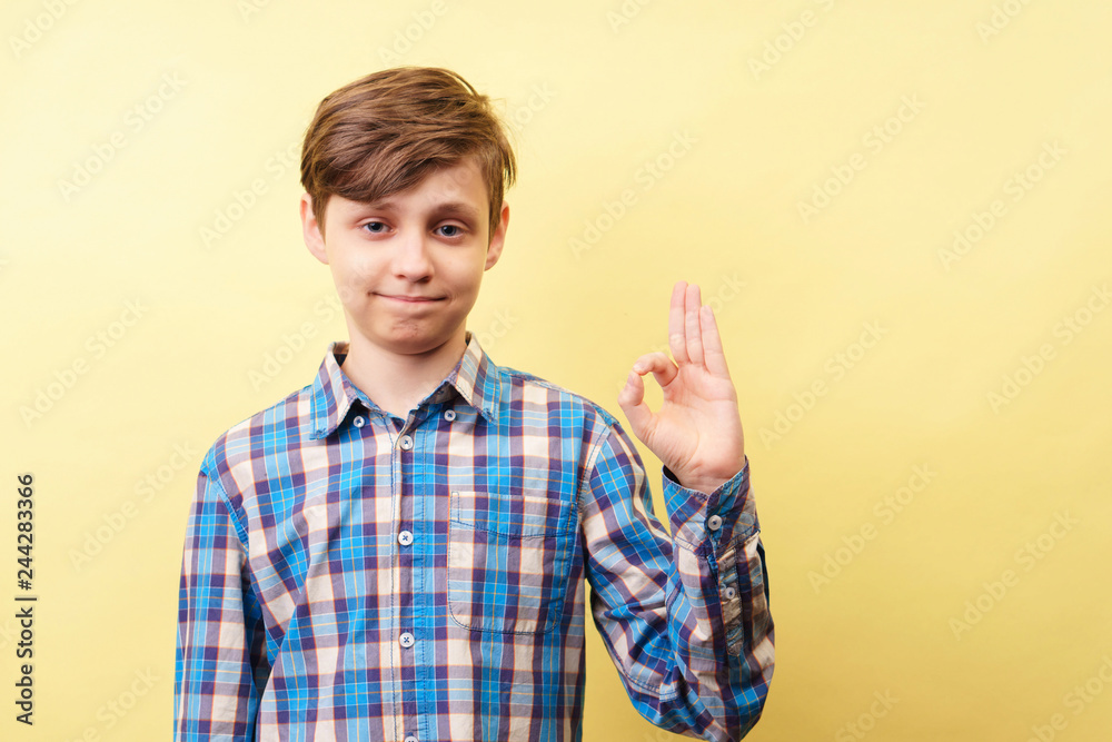 ok, satisfaction and approval. happy confident boy showing okay gesture over yellow background, advertisement, banner or poster template, emotion facial expression, people reaction ok, satisfaction and approval. happy confident boy showing okay gesture over yellow background, advertisement, banner or poster template, emotion facial expression, people reaction
