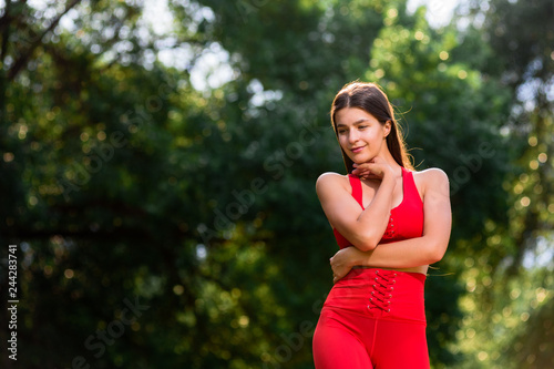 Portrait of beautiful young yoga woman posing in park