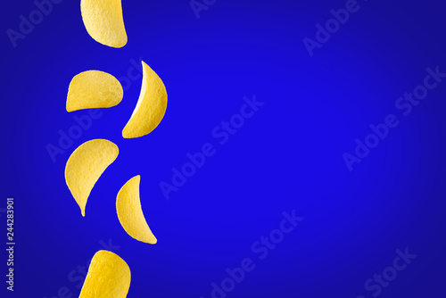 Falling potato chips isolated on blue background. Flying crispy snacks
