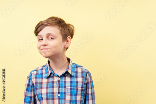  mocking jeering scoffing boy with ironical smile over yellow background, advertisement, banner or poster template, emotion, people reaction