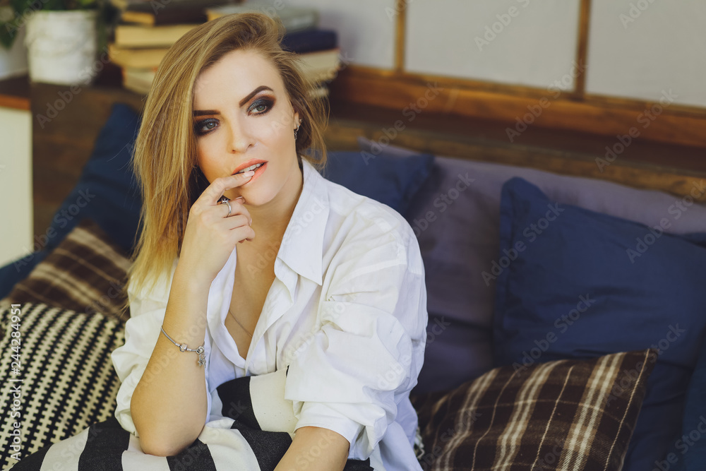 Young beautiful blonde girl in a white men's shirt on the bed Young beautiful blonde girl in a white men's shirt on the bed
