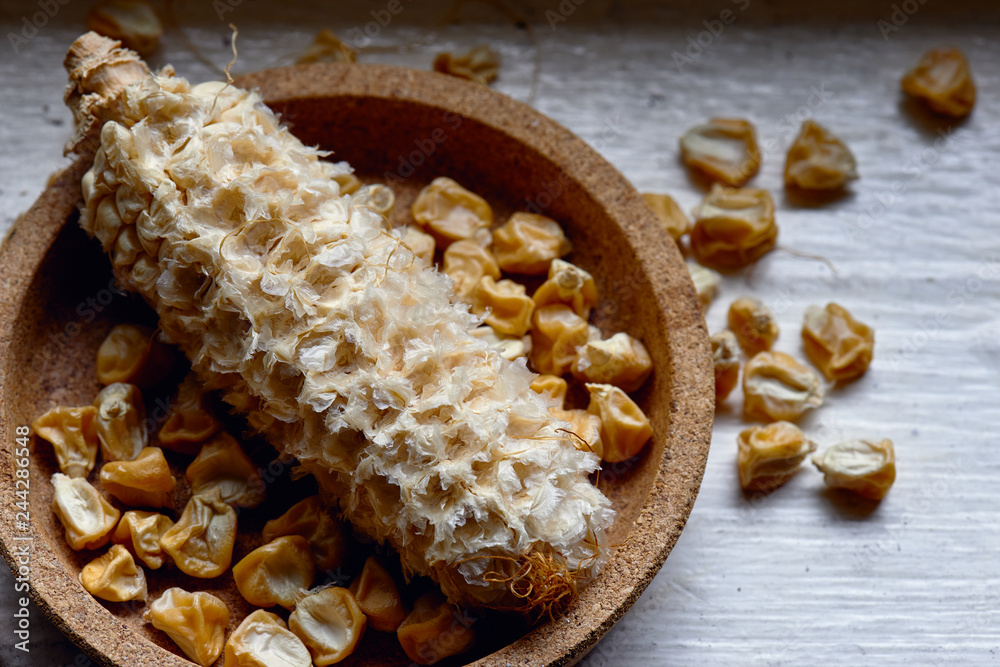 Fototapeta premium Dried sweet corn seed off the cob in a cork bowl ready for planting.