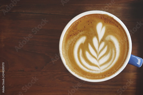 a cup of latte art coffee on wooden background