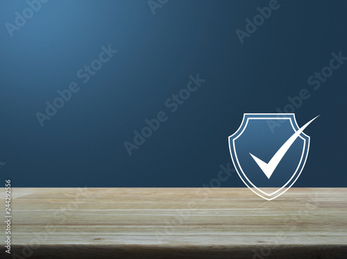 Security shield with check mark flat icon on wooden table over light blue gradient background, Technology internet cyber security and anti virus concept © grapestock