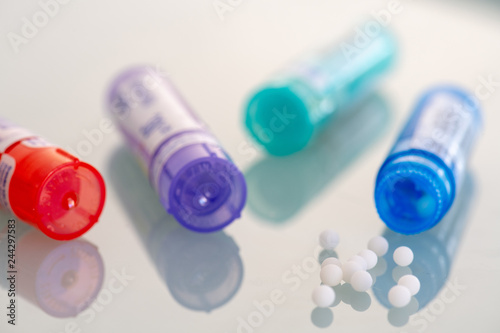 Homeopathic globules scattered around with their colored containers in the shape of tube