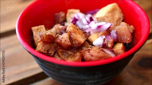 Handheld close up video shot of a bowl of chopped fried pork and tofu with soy sauce photo