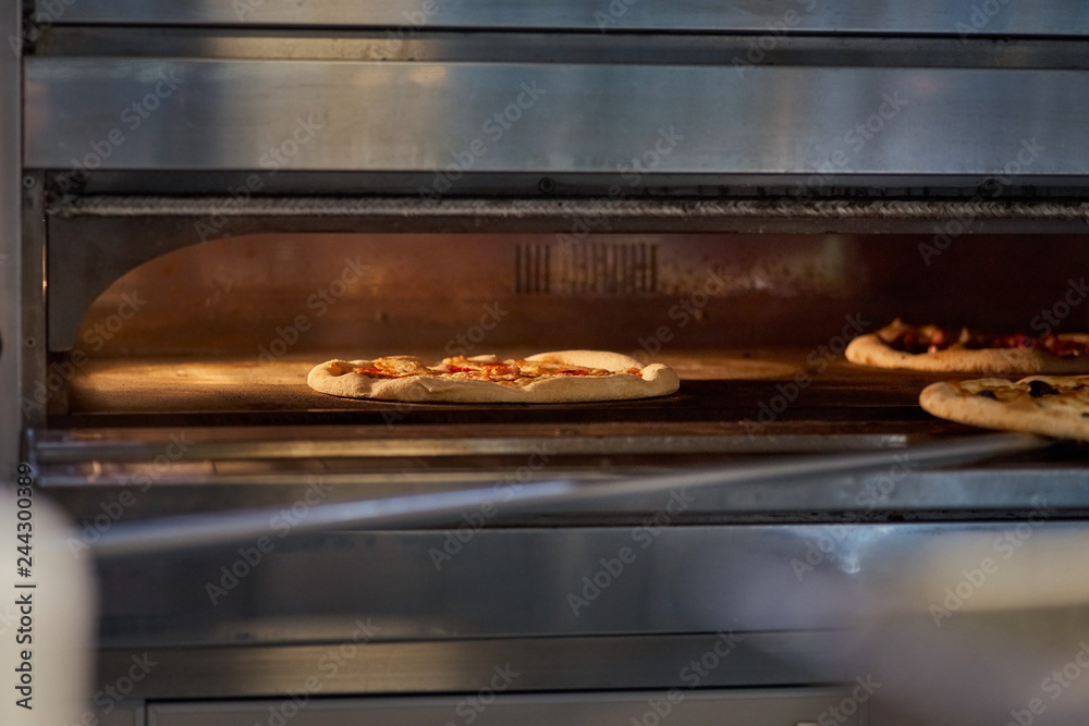 Cook putting Italian pizza to bake in oven. Preparation of pizza. selective focus, copy space. Cook putting Italian pizza to bake in oven. Preparation of pizza. selective focus, copy space.