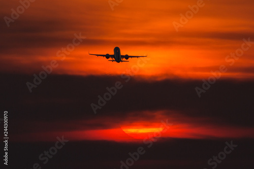 Air plane taking off at sunset near to the sun with beautiful red cloud in background