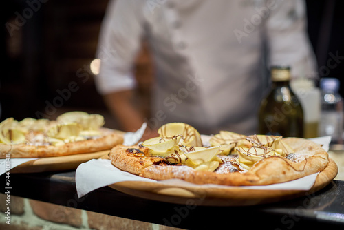 Cook in the kitchen putting the ingredients on the pizza. Pizza concept. Production and delivery of food.