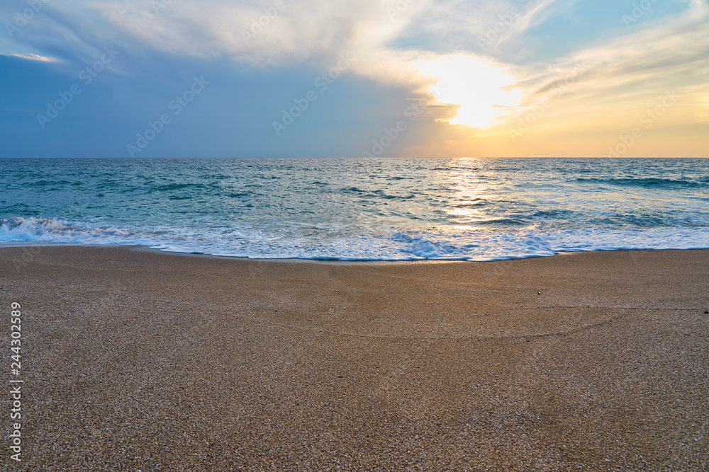 Sunset at the tropical beach, sun behind clouds reflects on water and waves with foam hitting sand. Sunset at the tropical beach, sun behind clouds reflects on water and waves with foam hitting sand.