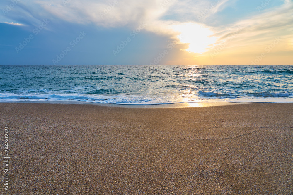 Sunset at the tropical beach, sun behind clouds reflects on water and waves with foam hitting sand. Sunset at the tropical beach, sun behind clouds reflects on water and waves with foam hitting sand.