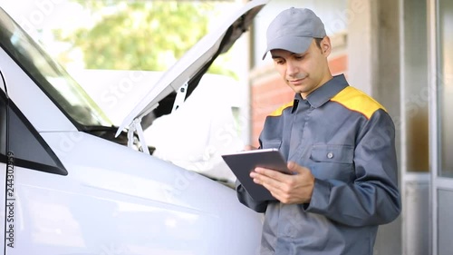 Mechainc using a tablet in front of a van