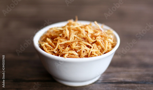Fried red onion on wood background. Can used as topping on the side with the chicken, meat or fish dishes.