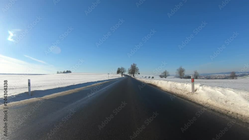 Car driving in through countryside in winter season, sunny day and landscape covered by snow, flat protune colors Car driving in through countryside in winter season, sunny day and landscape covered by snow, flat protune colors