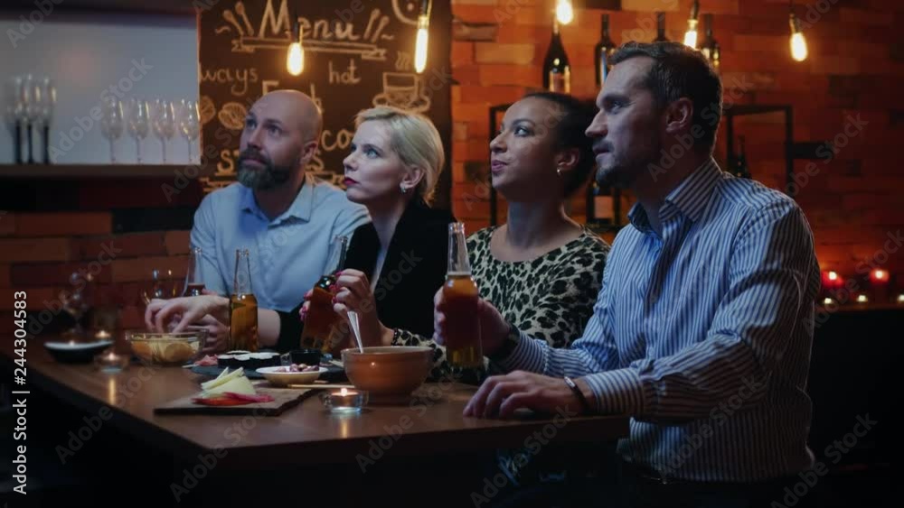 Group of friends wathching tv in a cafe behind bar counter