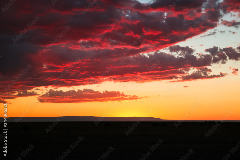 Fototapeta premium Dramatic sunset / dawn in Gobi Desert with stunning clouds and red sky (Gobi Desert, Mongolia, Asia)