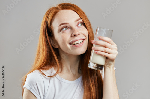 satidfied woman holding a glass of milkshake and dreaming. pleasant taste photo