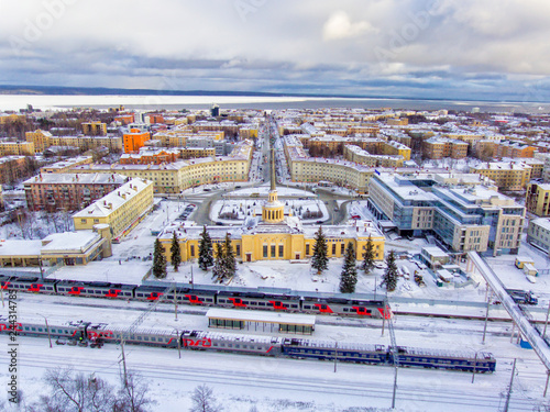 Railway station and train on platform in winter and city aerial panorama