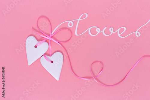 Valentines Day background concept. Two Hearts hangs on ribbon on pink paper background with copy space. Top view.