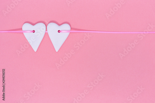 Two hearts together on same line on paper pink background. Valentines Day background concept.