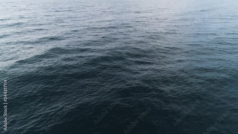 Top view of blue sea ripples. Shot. Background of water surface with smooth waves and ripples. Movement of blue surface of sea gives calm and pleasure