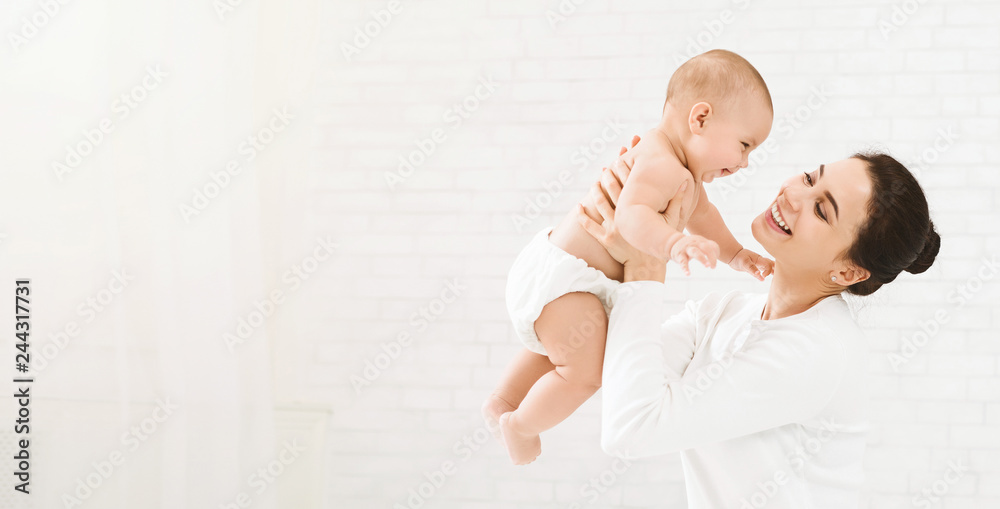 Young mom holding her happy baby in air - obrazy, fototapety, plakaty 