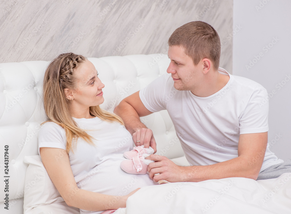 Beautiful pregnant woman and her husband is in their bedroom Beautiful pregnant woman and her husband is in their bedroom