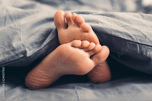 Female beautiful feet under blanket in bed © Prostock-studio