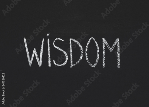 Word wisdom written on black chalkboard, copy space