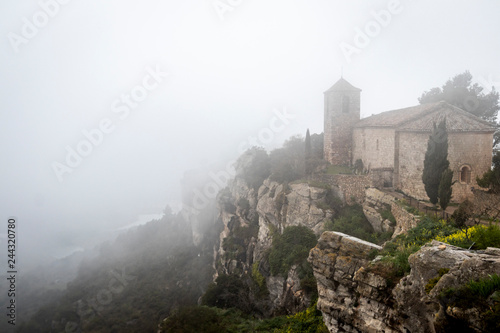 Iglesia de Santa María en la niebla de la ciudad medieval de Ciurana o Siurana sobre el riscal de la Sierra de la Gritella