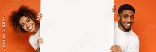 Young happy black couple holding blank board