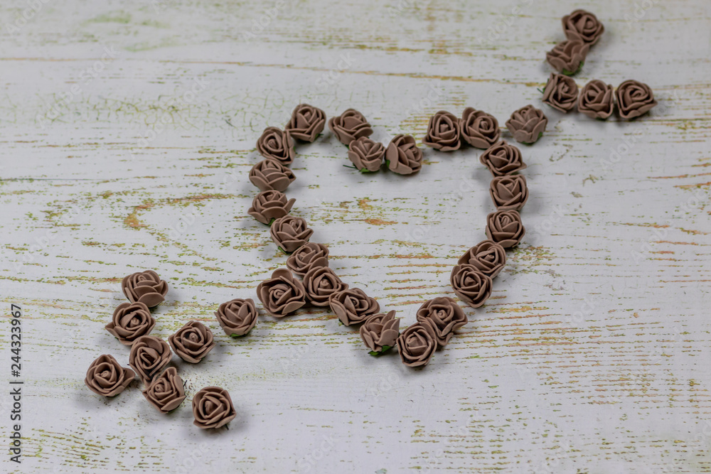 Heart pierced by an arrow made of brown roses. On wooden background, photo bokeh. Feast of love, Valentine's Day. Postcard with copy space. Heart pierced by an arrow made of brown roses. On wooden background, photo bokeh. Feast of love, Valentine's Day. Postcard with copy space.