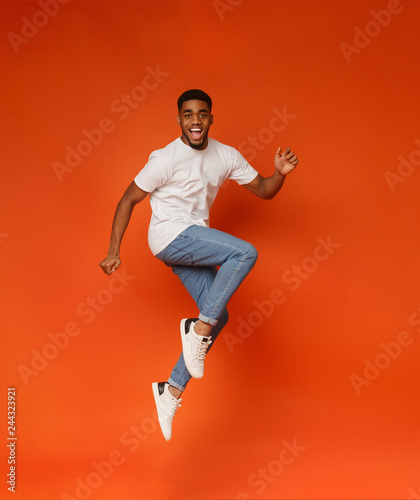 Canvas Print Excited african-american man jumping on orange background