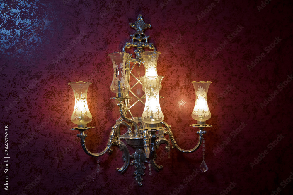 Stylish lamp on the wallpaper . Wall light of gilded metal with two electric candles . vintage wall lamp isolated on white with clipping path - Image Stylish lamp on the wallpaper . Wall light of gilded metal with two electric candles . vintage wall lamp isolated on white with clipping path - Image