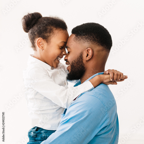 Father hugging with daughter, touching foreheads in studio photo