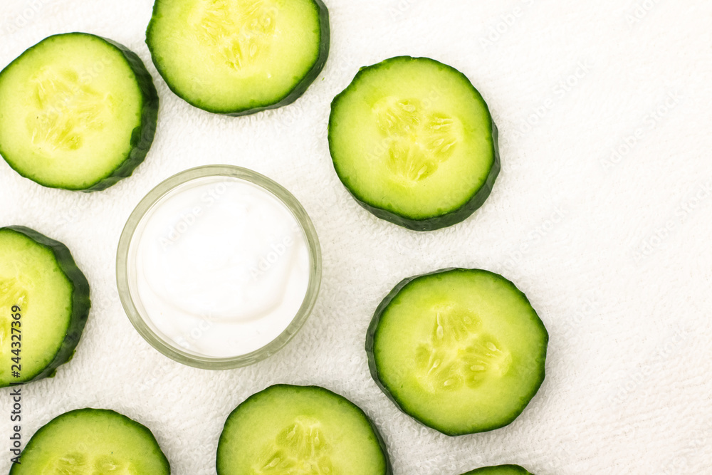 Background from cream and sliced cucumbers on a white towel Background from cream and sliced cucumbers on a white towel