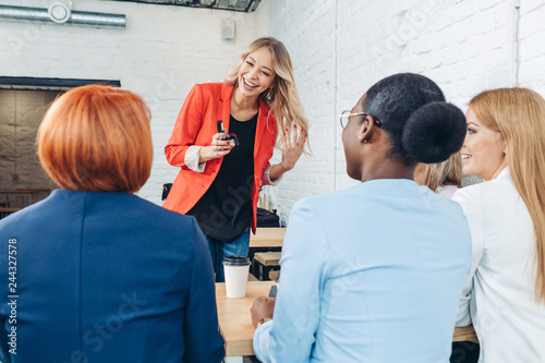 Blonde female employee make presentation for diverse co-workers during meeting in office cafe