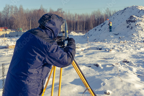 The cadastral service worker conducts surveying and topographic measurements photo