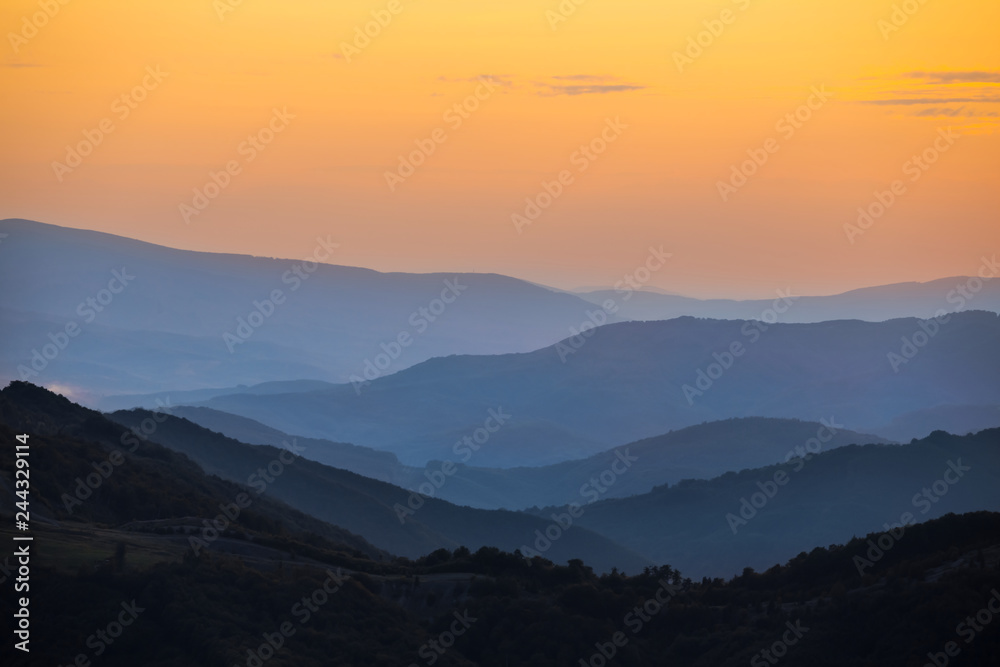 Obraz premium mountain chain silhouette in a blue mist at the evening