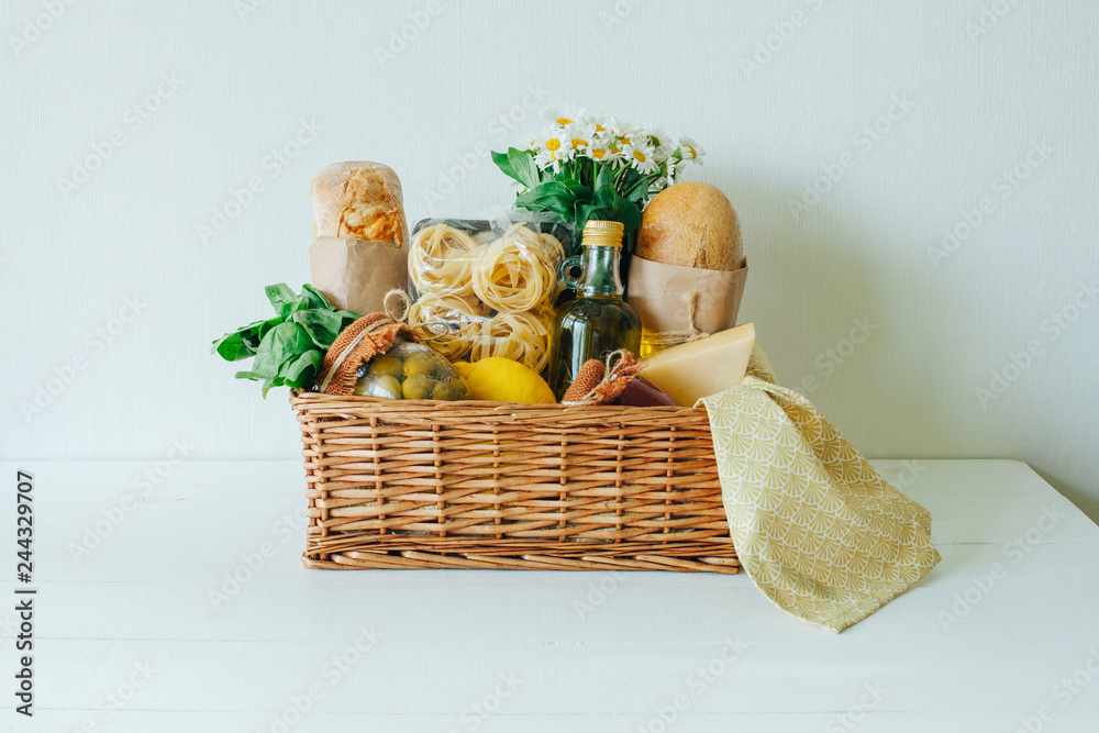 Italian food basket with bread, basil, olive oil, lemons, and a bottle of wine. Italian food basket with bread, basil, olive oil, lemons, and a bottle of wine.
