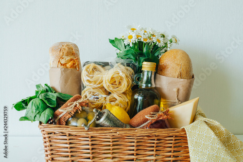 Italian food basket with bread, basil, olive oil, lemons, and a bottle of wine. photo