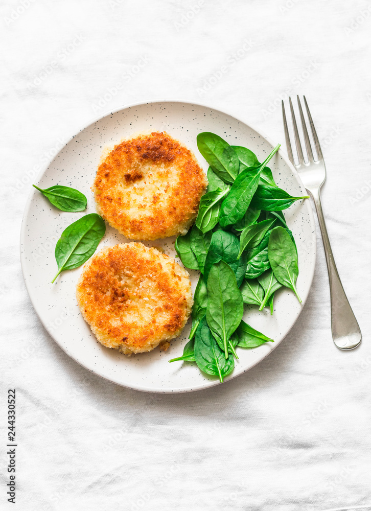 Potato bread crumbs baked cakes with spinach on a light background, top view. Delicious vegetarian lunch