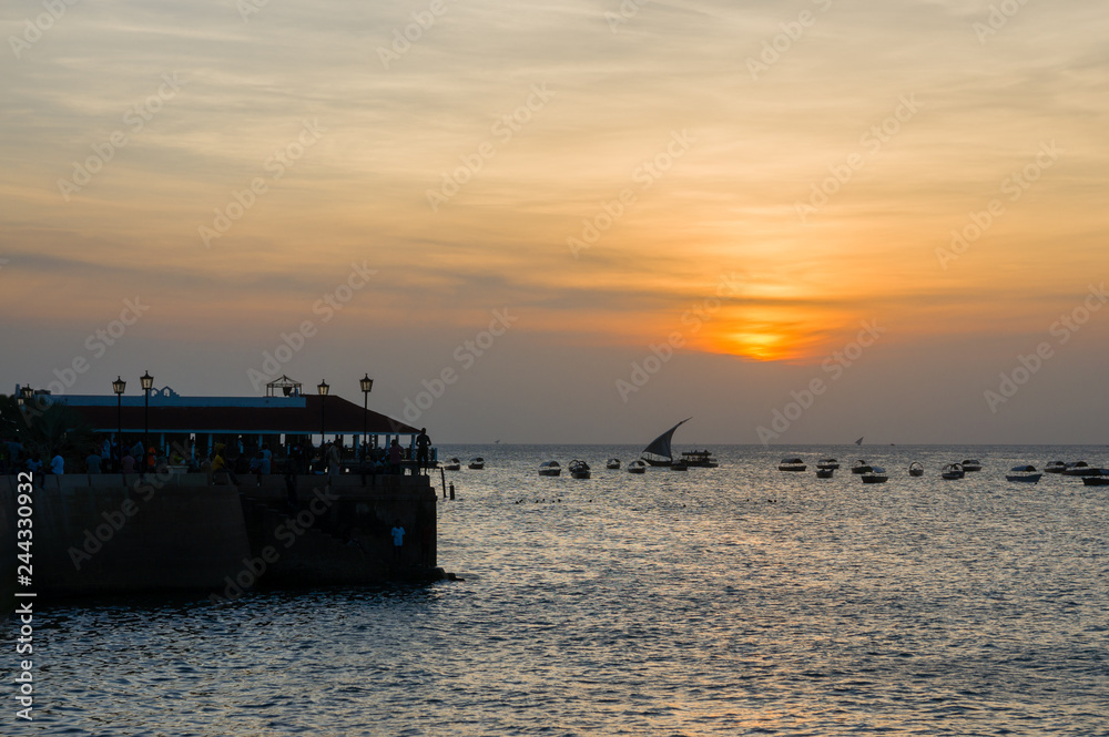 Children jump from the pier into the sea. Silhouettes at sunset. Summer travel.Stone Town, Zanzibar, Tanzania.