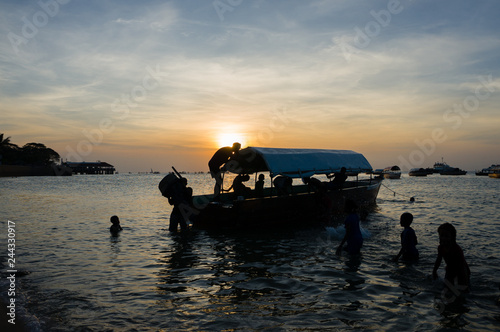Silhouette-Many children are playing beside the boat.Beautiful sunset, Stone Town, Zanzibar, Tanzania.