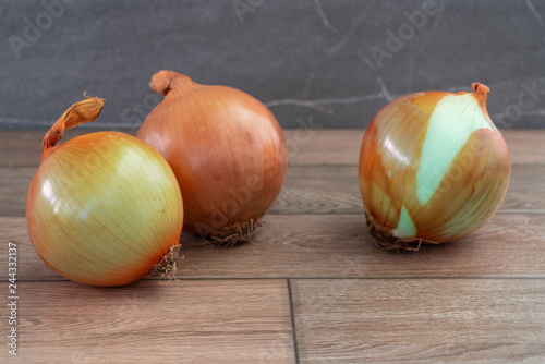 Three onions on wooden floor
