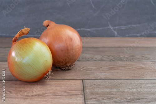 Two onions on wooden floor.
