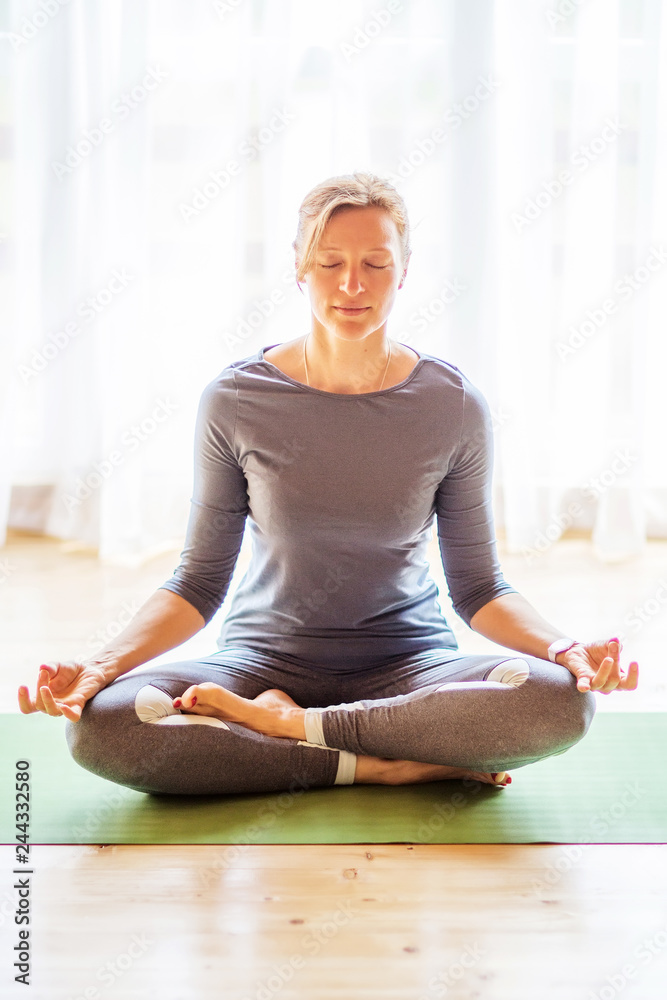Caucasian woman is practicing yoga at studio