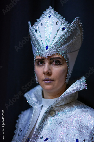 The snow queen looked straight at you. Festive costumes for carnival on a black background.