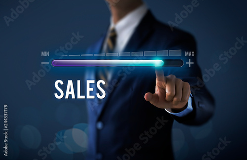 Sales growth, increase sales or business growth concept. Businessman is pulling up progress bar with the word SALES on dark tone background.